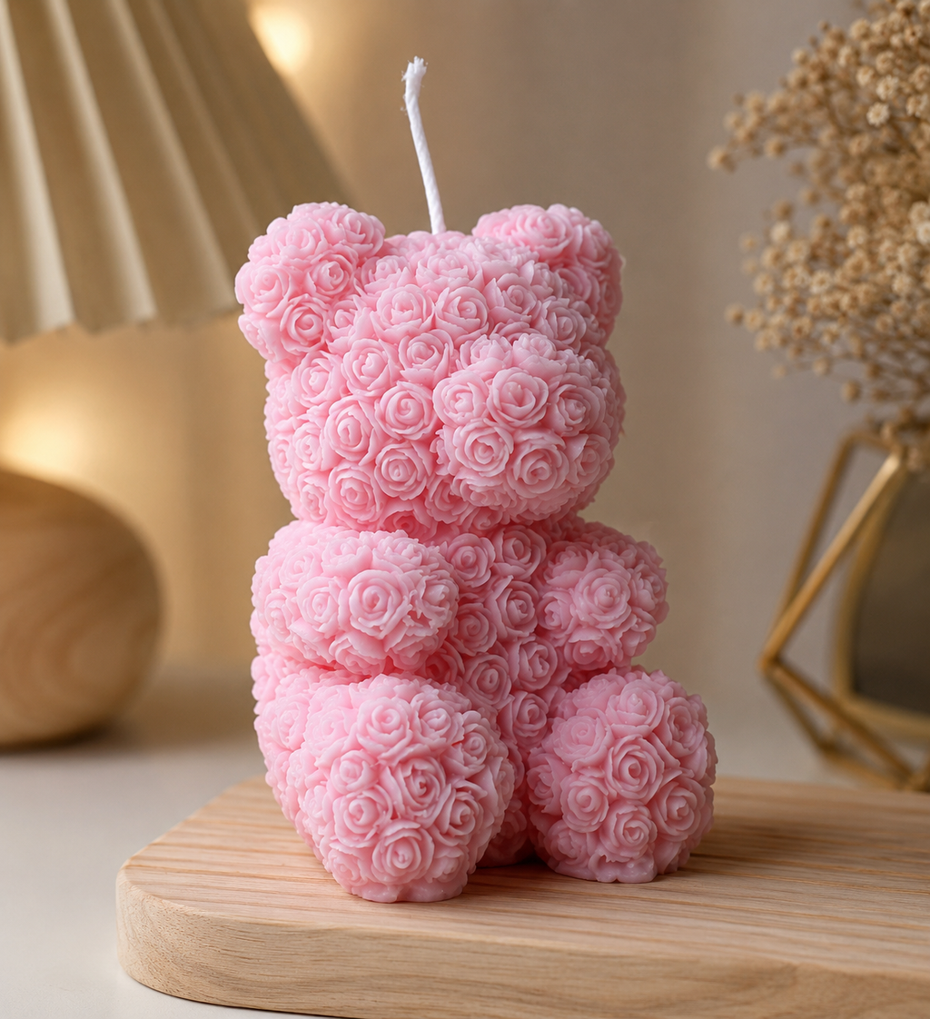 Pink teddy bear-shaped candle on a wooden surface with a blurred background