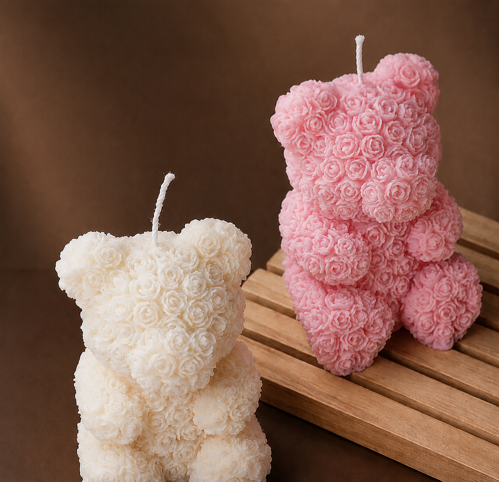 Two bear-shaped candles, one white and one pink, on a wooden surface with a brown background.